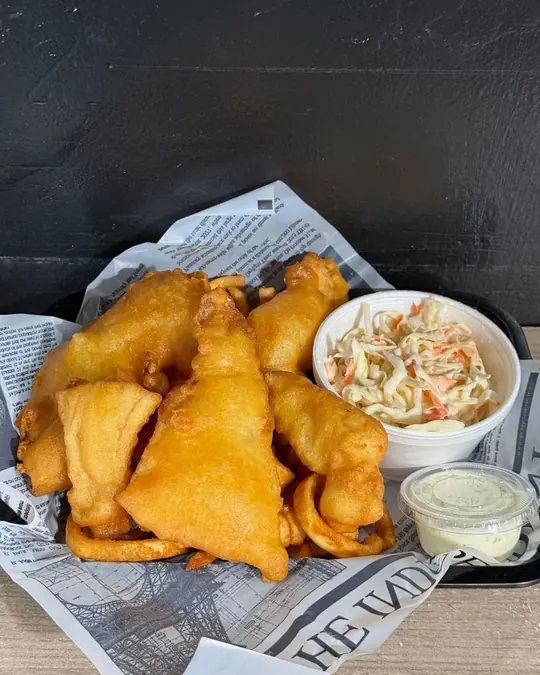 Battered fried fish with coleslaw and tartar sauce on newsprint